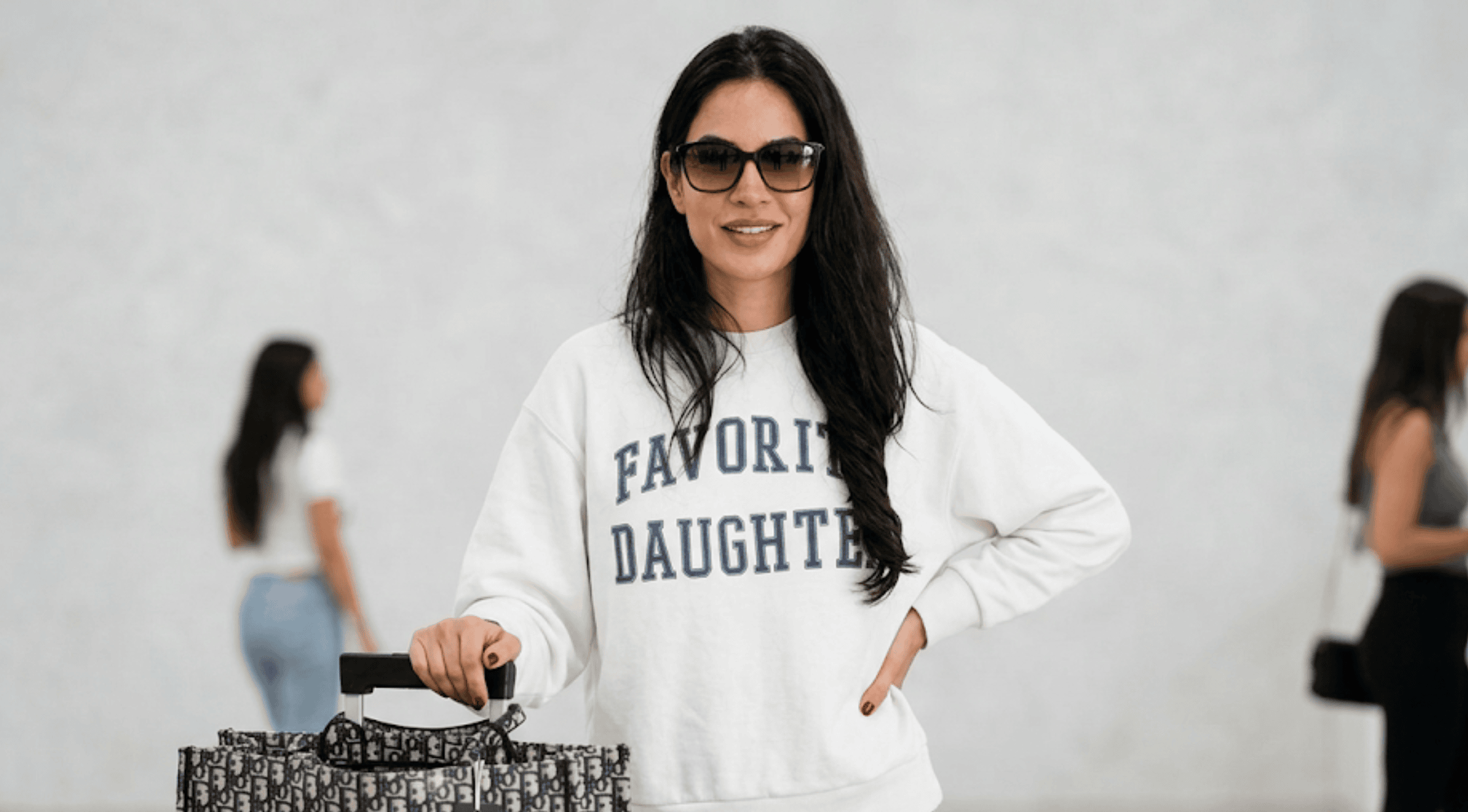 Michelle Saniei The Valley Season 3 white crewneck sweatshirt with navy blue Favorite Daughter varsity lettering.